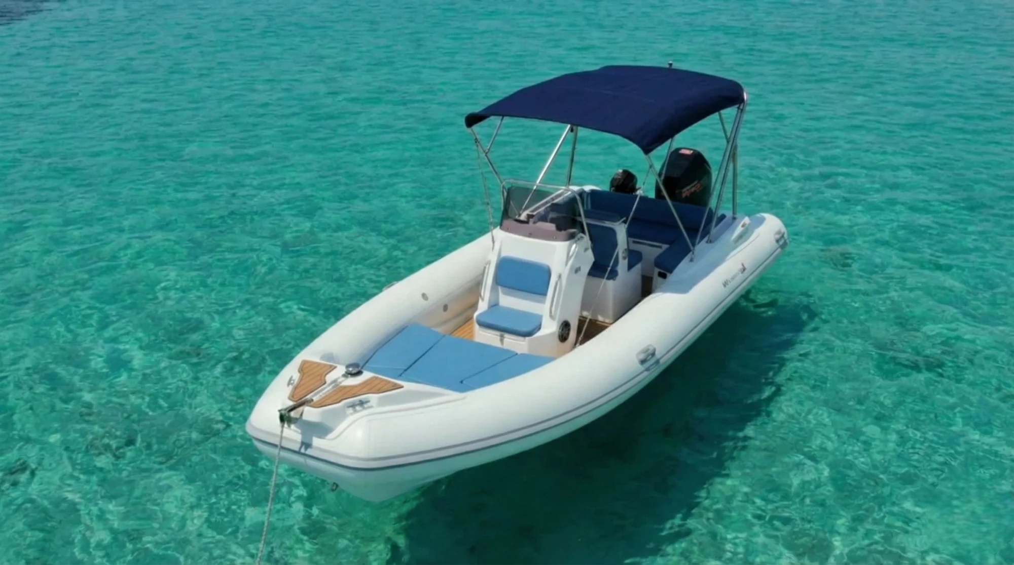 Gommone azzurro con prendisole di prua e tendalino nero.