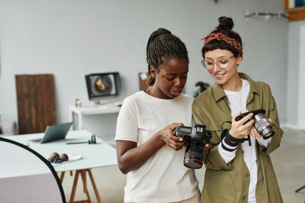 Due persone in studio esaminano fotocamere: una mostra lo schermo, l’altra tiene una fotocamera compatta.